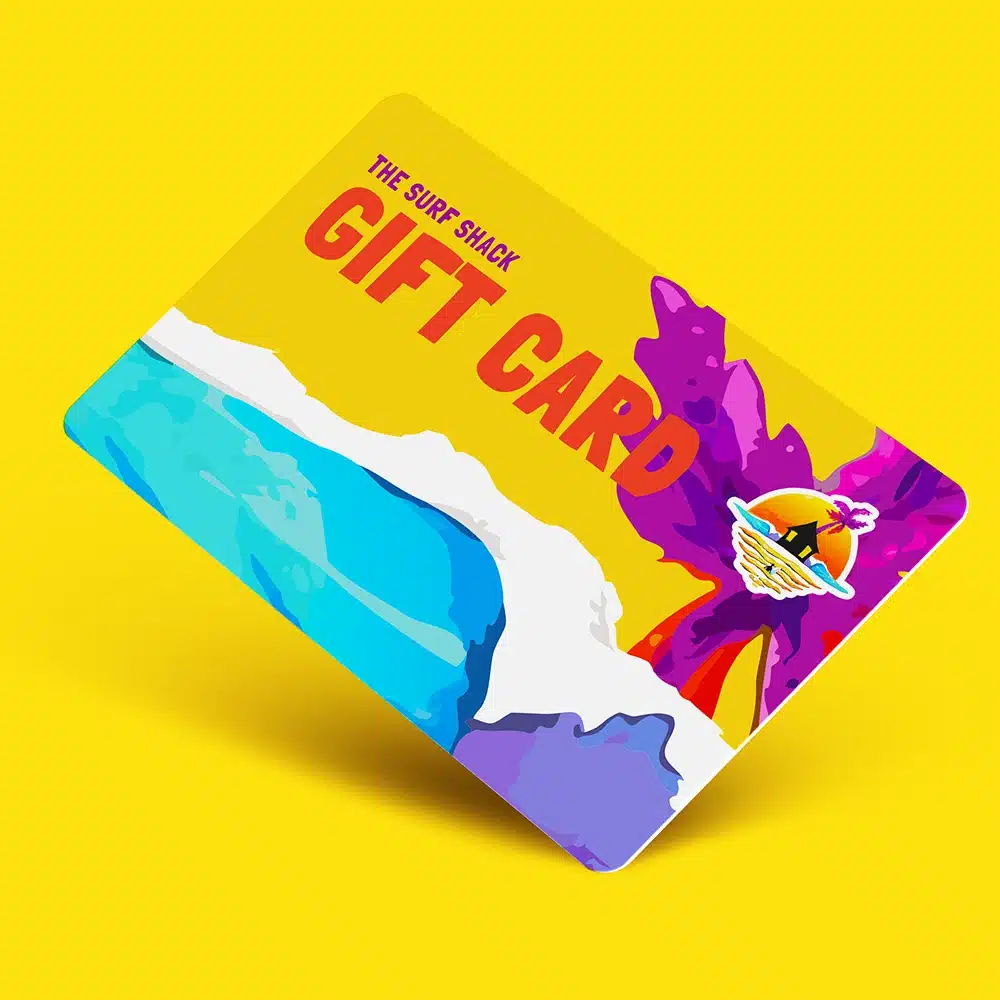 A colourful gift card for "The Surf Shack" features bold red text, a beach scene with blue ocean waves, white sand, and a purple palm tree, set against a bright yellow background.