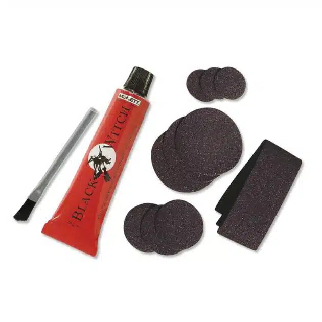 The Blackwitch Neoprene Repair Kit includes a tube of Black Witch adhesive, a metal rasp, a small brush, and assorted round and rectangular black repair patches for bicycle tyres.