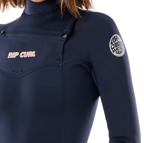 A woman wearing the Ripcurl Women’s Dawn Patrol 4/3mm Chest Zip Wetsuit in navy blue, featuring a high collar and logo patches on the chest and upper sleeve; only her upper body is visible.
