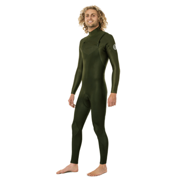 A barefoot man with curly blond hair smiles whilst wearing the Rip Curl Men's Dawn Patrol 5/3mm Chest Zip Wetsuit, a full-body, dark green wetsuit with long sleeves and a high collar, standing against a plain white background.