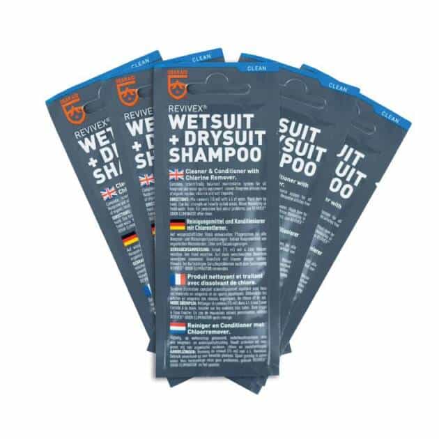 Five GearAid Revivex Wetsuit Shampoo 15ml sachets are fanned out, displaying front labels in English, German, French, and Dutch, with blue packaging and orange accents.