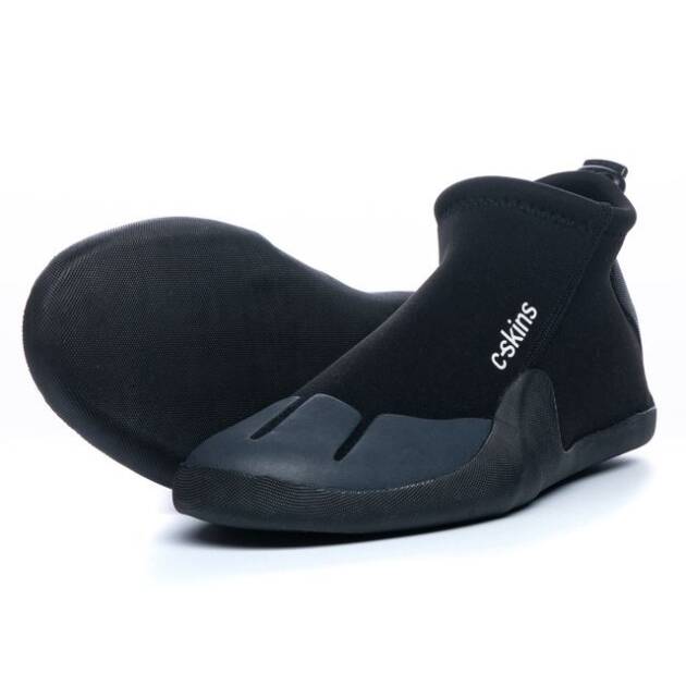 A pair of C-Skins Legend 3mm Round Toe Reef Boots in black features a minimalist design with the "C-Skins" logo on the side. One boot stands upright, whilst the other lies sideways displaying its distinctive sole.